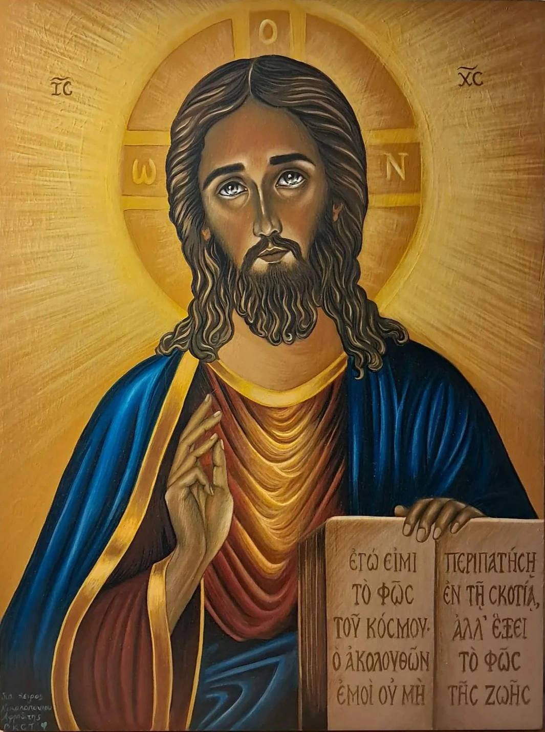 Jesus Christ Pantocrator holding an open Gospel and raising His hand in blessing, against a golden background.
